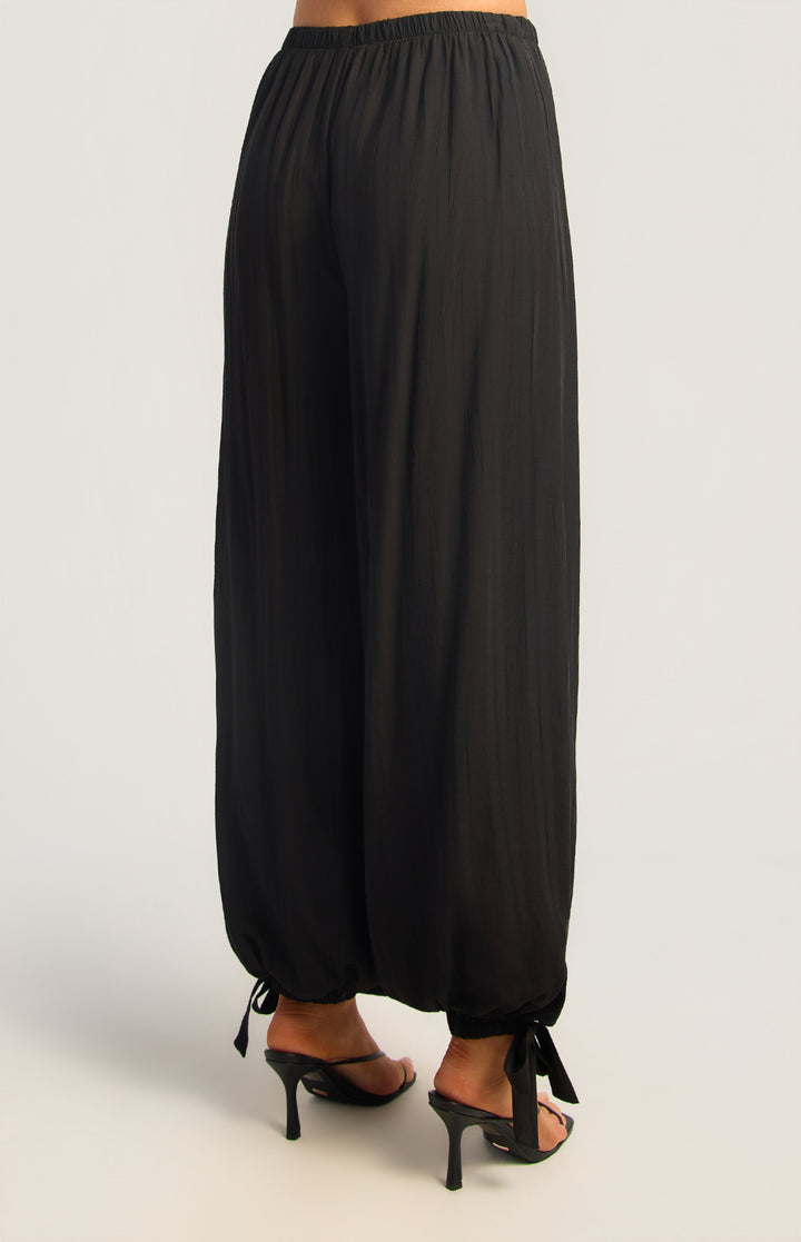 Textured balloon hem pants in black, back three-quarter view